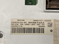 Close-up label on a vehicle control module showing part number 68235673AA, Chrysler (P), Japan 5.7L, and a barcode.