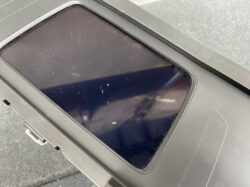 Close-up of a dark, dusty touchscreen on a rugged device, showing scratches on the glass and a black bezel surrounding the display.