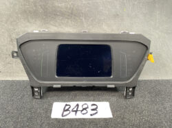 Vehicle instrument cluster module with a central rectangular display and side gauge areas on a mounting frame.