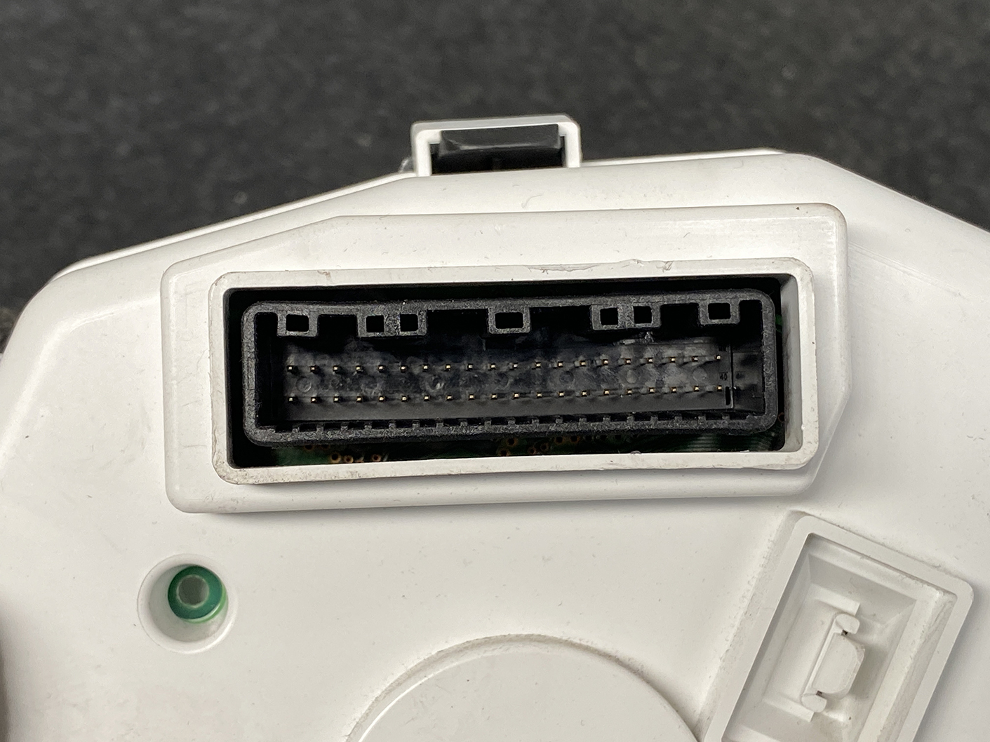 B484_4 SUBARU IMPREZA SPORTS GT2 Genuine Instrument Cluster 85002FL300 / NS0 9001K » NZ1.95 » JDM-PARTS NZ » JDM-PARTS NZ Close-up of a white device showing a wide rectangular multi-pin connector with two rows of small gold pins inside a dark housing; a green indicator light sits nearby. SUBARU IMPREZA SPORTS GT2 Genuine Instrument Cluster 85002FL300 / NS0 9001K » JDM-PARTS NZ