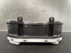 Black automotive electronic module with two mounting lugs and a clear lid, on a dark workbench.