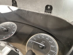 Close-up of a car dashboard showing speedometer (0–140 km/h) and tachometer, with two mounting brackets at the top.