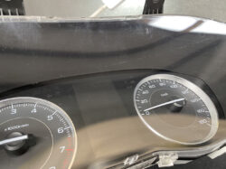 Instrument cluster of a car: left tachometer up to 7,000 rpm and right speedometer up to 180 km/h, with glass glare and reflections visible.