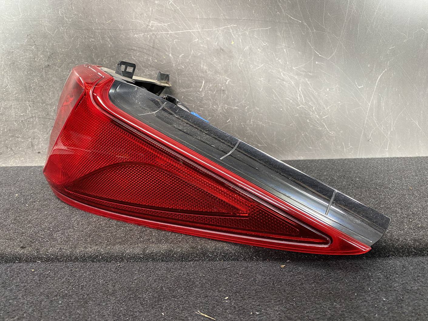 B485_4 MAZDA PREMACY CW NISSAN LAFESTA Taillight P9377 Right Side x1 » NZ1.95 » JDM-PARTS NZ » JDM-PARTS NZ Red automotive tail light assembly with black upper housing, resting on a dark textured surface. MAZDA PREMACY CW NISSAN LAFESTA Taillight P9377 Right Side x1 » JDM-PARTS NZ