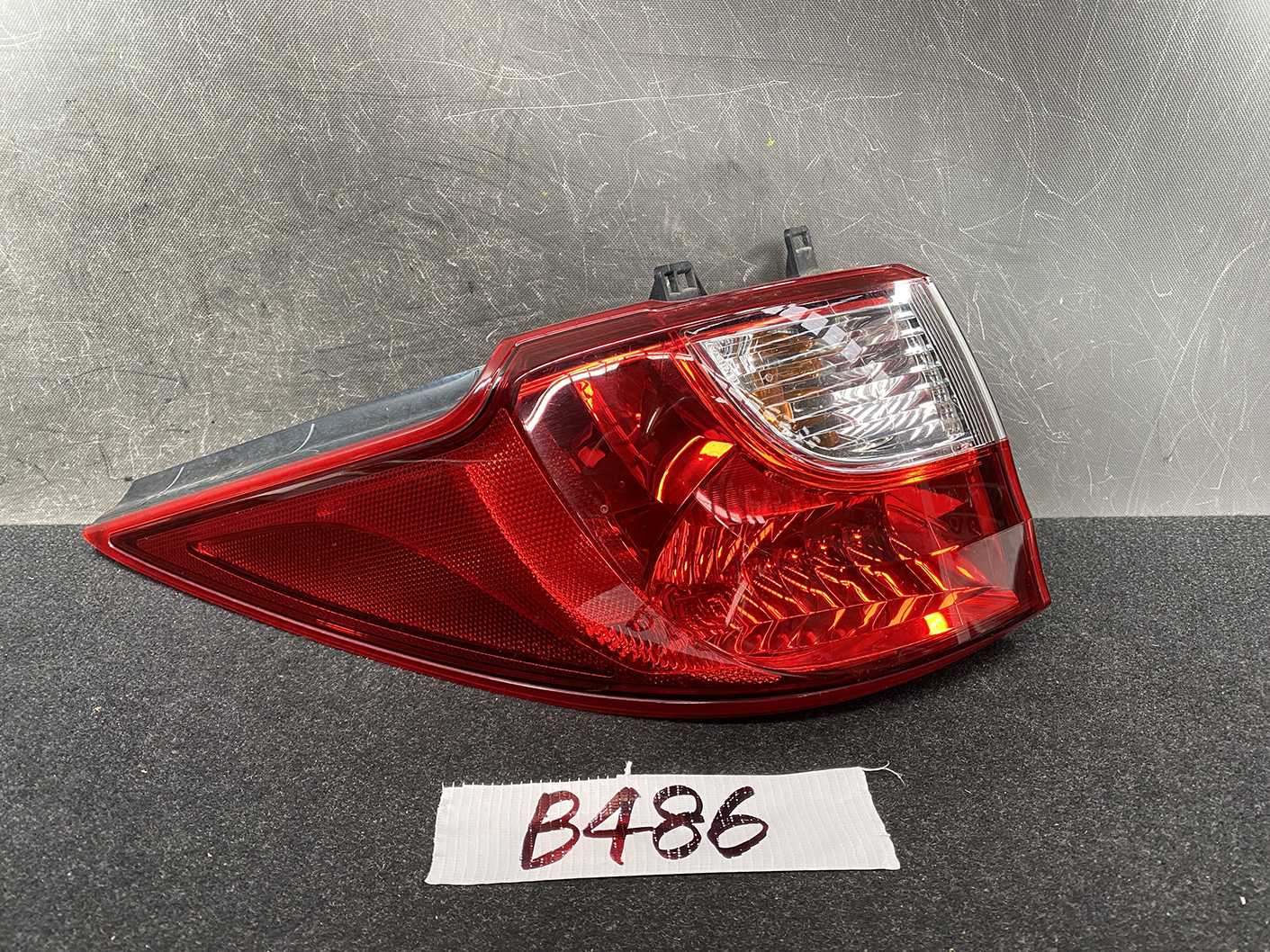 B486_1 MAZDA PREMACY CW NISSAN LAFESTA Taillight STANLEY P9377 L Left Side x1 » NZ1.95 » JDM-PARTS NZ » JDM-PARTS NZ Car tail light assembly with red lens and clear reverse light section on a dark surface. MAZDA PREMACY CW NISSAN LAFESTA Taillight STANLEY P9377 L Left Side x1 » JDM-PARTS NZ