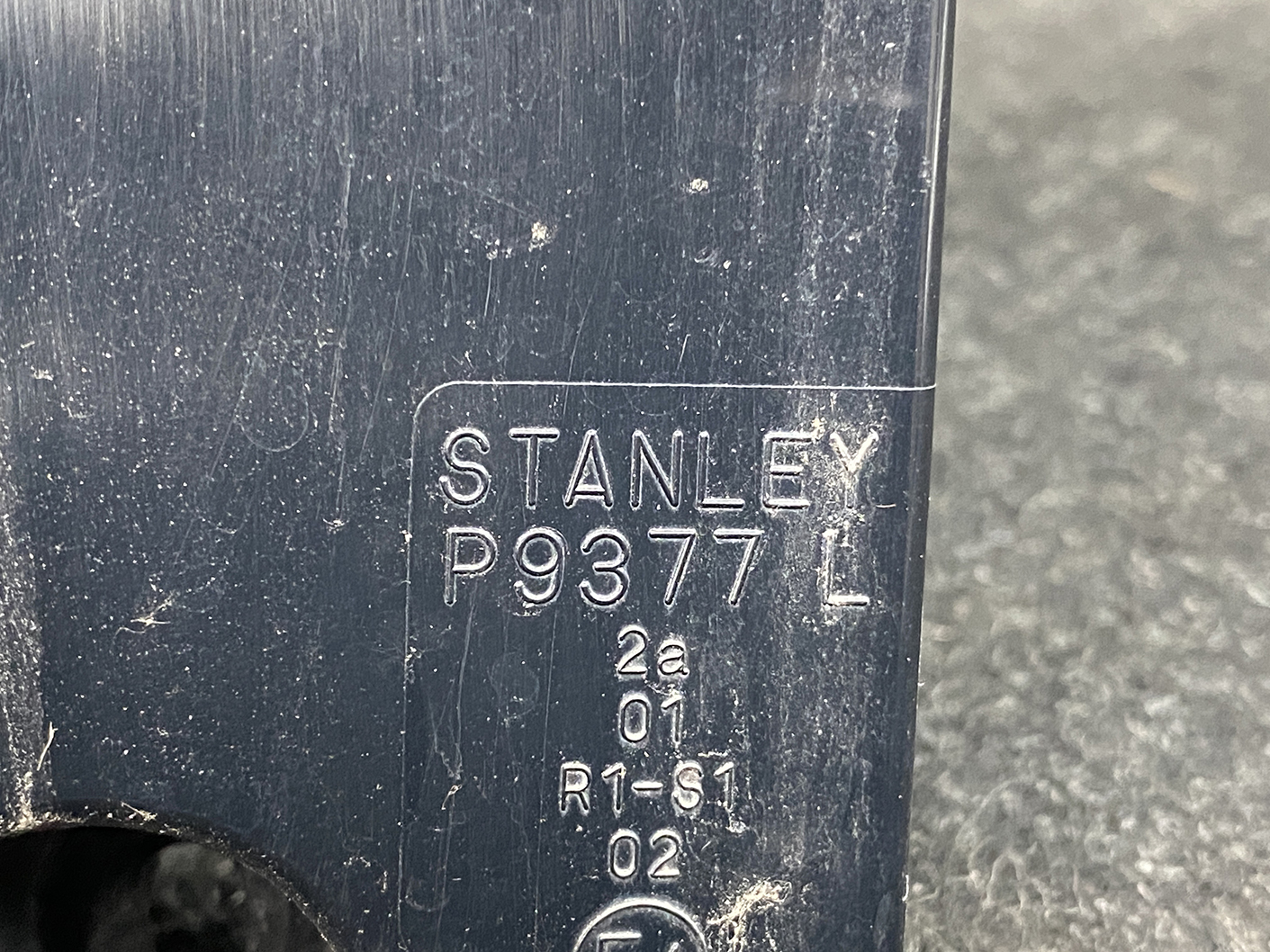 B486_2 MAZDA PREMACY CW NISSAN LAFESTA Taillight STANLEY P9377 L Left Side x1 » NZ1.95 » JDM-PARTS NZ » JDM-PARTS NZ Close-up of a dark blue plastic surface with a raised Stanley label reading P9377 and additional small stamped codes (L, 2a, 01, R1-S1, 02). MAZDA PREMACY CW NISSAN LAFESTA Taillight STANLEY P9377 L Left Side x1 » JDM-PARTS NZ