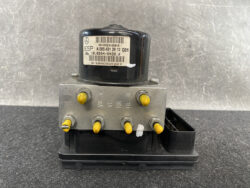 Automotive ABS/ESP brake modulator unit with a gray connector block and yellow pin posts on a black base