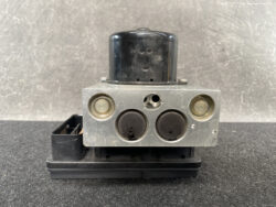 Automotive ABS brake actuator module with pump and valve block mounted on a plastic base.