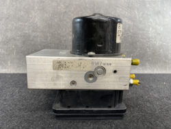 ABS brake module: silver valve block with black motor and yellow connector pins.