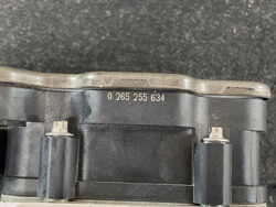 Close-up of a black automotive electrical component with embossed serial number 0 265 255 634 and metal fasteners.