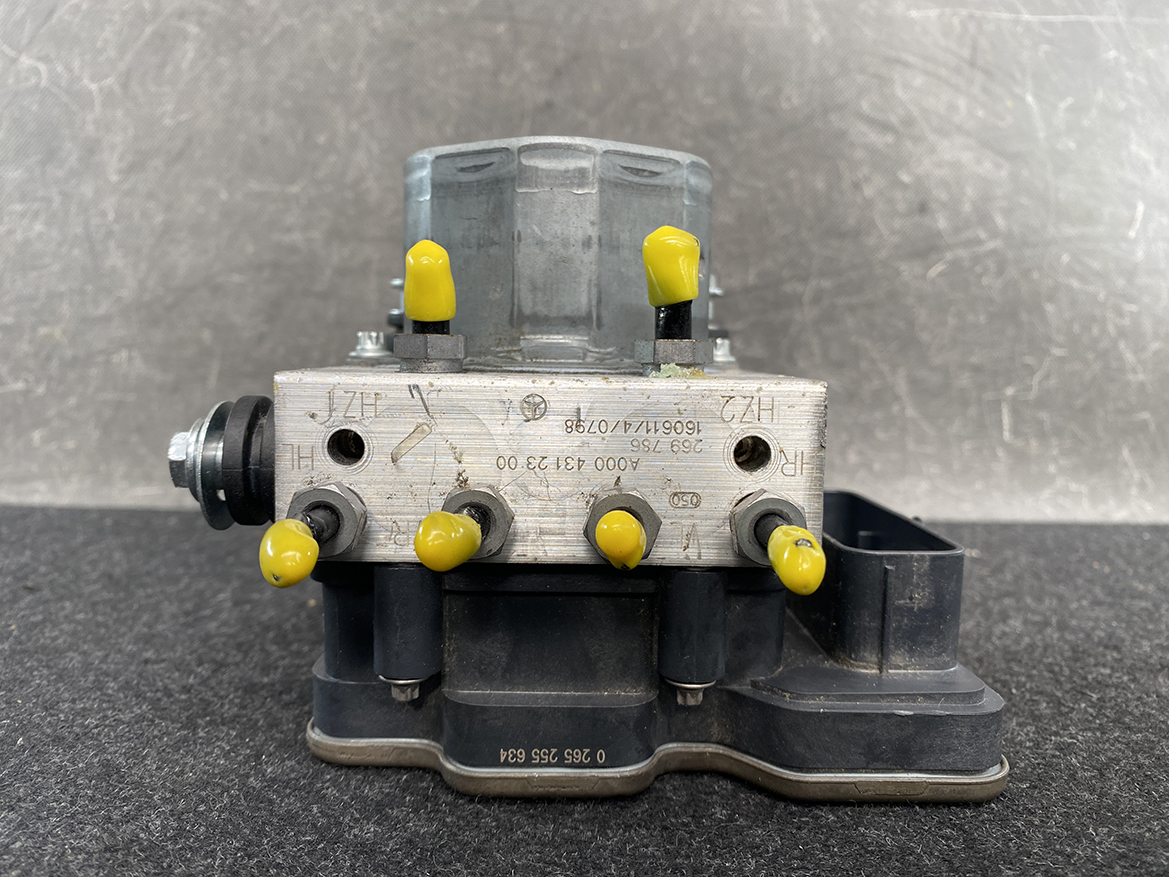 BNZ-ACTR-A000431 _8 Mercedes Benz Genuine ABS Actuator Pump A000 431 23 00 / 0 265 255 634 » NZ9.95 » JDM-PARTS NZ » JDM-PARTS NZ Close-up of an automotive ABS hydraulic valve block with yellow protective caps, mounted on a black base. The metal plate has stamped numbers and fittings are visible on the sides. Mercedes Benz Genuine ABS Actuator Pump A000 431 23 00 / 0 265 255 634 » JDM-PARTS NZ
