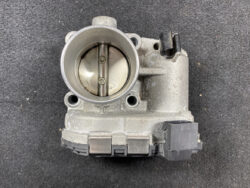 Throttle body intake with circular bore and two butterfly valves visible inside.