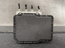 Automotive engine control unit with four terminal posts and a metal mounting plate behind a black plastic enclosure.