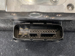 Close-up of a vehicle's electronic control unit (ECU) connector with multiple pin sockets inside a black plastic housing.