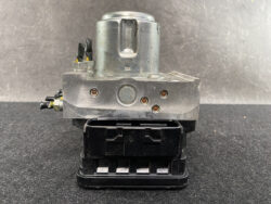 Automotive ABS pump and hydraulic control module with metal valve block and black connector housing.