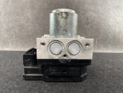 ABS brake actuator module with two circular pistons on a metal block and black mounting base