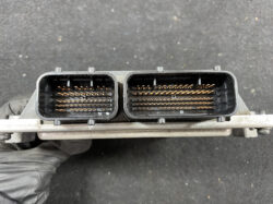 Two identical rectangular electrical connectors with dense gold pins, held side by side by a gloved hand.