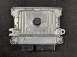 Metal automotive electronic control unit (ECU) housing with mounting flanges and a black connector at the bottom on a dark surface.