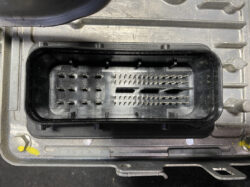 Close-up of a multi-pin automotive ECU connector receptacle with densely packed pins in a black housing
