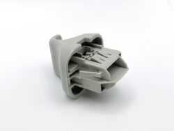Gray plastic multi-pin electrical connector viewed from side, showing internal pin slots and alignment tabs