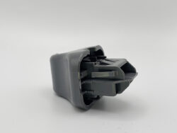 Close-up of a gray plastic automotive switch module, showing its mechanical latch parts and internal structure.