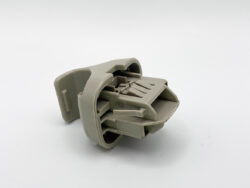 Gray plastic automotive electrical connector housing with multiple slots for pin contacts, shown from a side angle on a white background