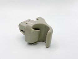Gray plastic clamp-style connector part with a rounded U-shaped channel, likely used to hold or guide a cable or tube.