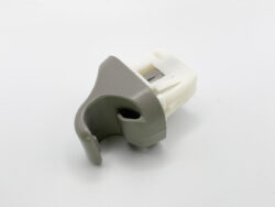 Grey curved plastic car interior trim piece with a white plastic connector at the back, likely a small automotive clip or lever component.