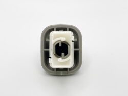 Close-up of a gray square plastic connector housing with a white inner insert and a circular hollow center viewed from the front.