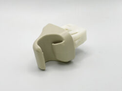 White plastic orthodontic appliance part with a curved hook on a plain background.