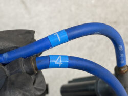 Blue automotive wires with numbered tags 1 and 4 connected to a black component against a gray background.