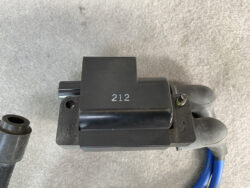 Black ignition coil with attached blue spark plug wires and '212' stamped on the housing
