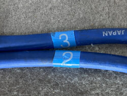 Two blue hoses with light blue tags labeled '2' and '3' resting on a gray carpeted floor.