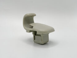 Gray plastic automotive interior part resembling a small seat or latch assembly, shown from the side.