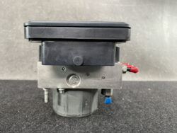 Industrial valve actuator unit with black plastic cover and metal body, featuring red and blue quick-connect fittings and a gray knob.
