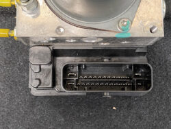 Close-up of a metal bracket with a black multi-pin connector port showing two rows of metal pins inside a recessed socket.
