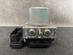 Automotive brake control module with two round ports and a central shaft mounted on a black plastic base