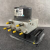 Automotive ABS hydraulic modulator with multiple yellow-tipped connectors mounted on a black base, labeled with part numbers on a cylindrical black component (for vehicle braking system). Nissan X-Trail Genuine ABS Actuator Pump 47660-4CA7A / 269620 » JDM-PARTS NZ