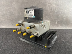 Automotive ABS hydraulic modulator with multiple yellow-tipped connectors mounted on a black base, labeled with part numbers on a cylindrical black component (for vehicle braking system).