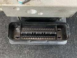 Close-up of a two-row, multi-pin automotive connector in a black plastic housing with pins labeled 32–47, mounted under a metal panel.