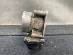 Dusty side-view of an industrial metal actuator or valve mounted on a bracket, with a cylindrical housing and mounting flange visible.