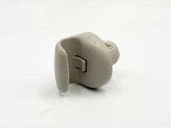 Beige plastic mechanical component with a small side latch and cylindrical tail, viewed from the side.