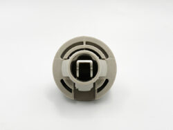 Close-up of a round beige plastic mechanical part with a hollow center and square opening, likely a connector or collar.v