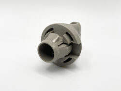 Gray plastic hose fitting with a central bore and locking features for tubing attachment, shown from an angled view.