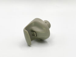 Beige silicone earplug/ear mold with a small vent resting on a white background