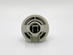Front view of a gray circular plastic connector with a central square opening and surrounding grooves/slots.