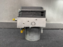 Bosch ABS hydraulic brake actuator module with a metal mounting plate and yellow quick-connect fittings.