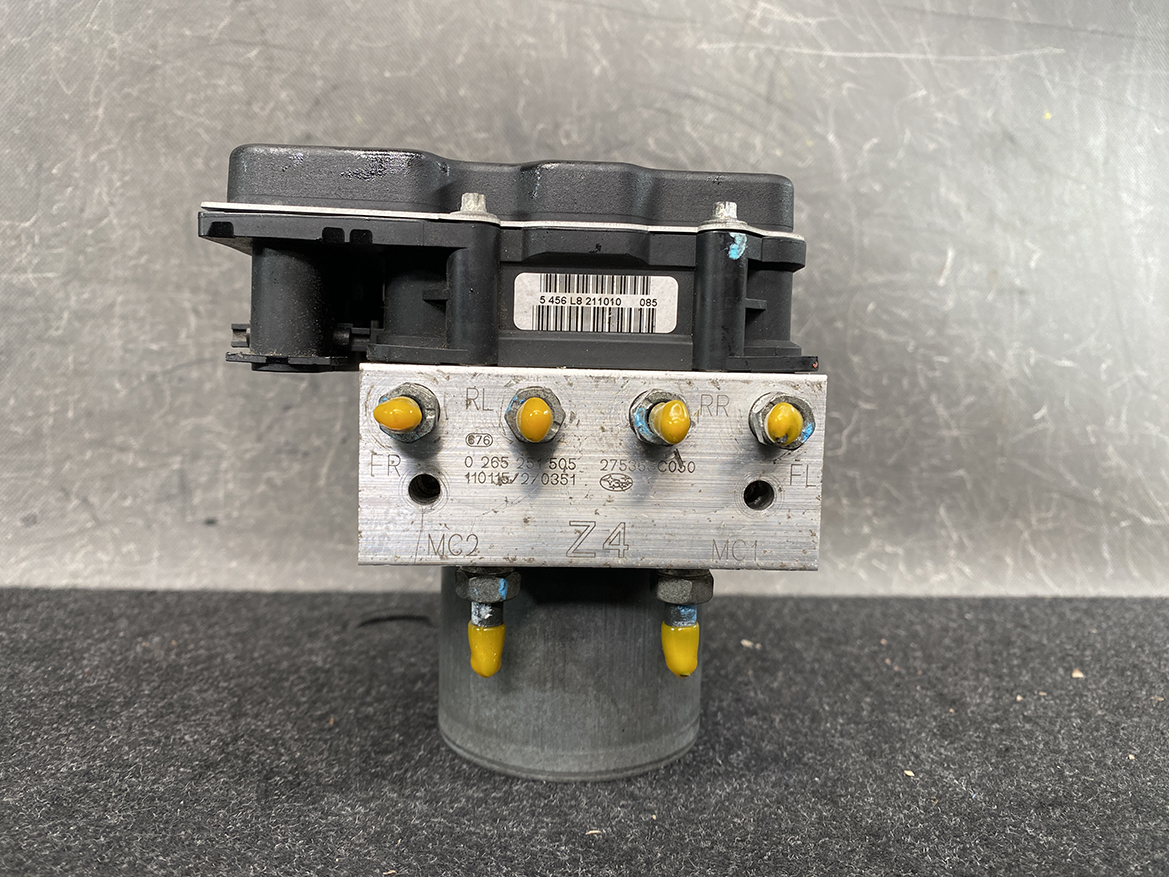 SUB-ACTR-27536SC050_4 Subaru Forester Genuine ABS Pump Module Actuator 27536SC050 » NZ9.95 » JDM-PARTS NZ » JDM-PARTS NZ Automotive ABS brake modulator with yellow sensors and a metal valve block, shown on a gray work surface. Subaru Forester Genuine ABS Pump Module Actuator 27536SC050 » JDM-PARTS NZ