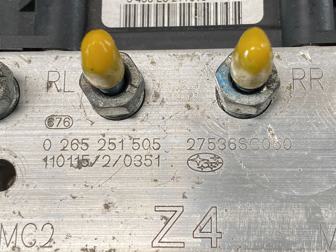 SUB-ACTR-27536SC050_5 Subaru Forester Genuine ABS Pump Module Actuator 27536SC050 » NZ9.95 » JDM-PARTS NZ » JDM-PARTS NZ Close-up of a dirty metal engine plate with two yellow-tipped stud nuts labeled RL and RR, along with stamped part numbers and a small Subaru oval logo. Subaru Forester Genuine ABS Pump Module Actuator 27536SC050 » JDM-PARTS NZ