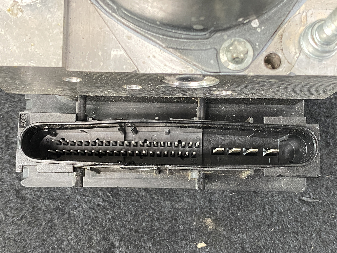 SUB-ACTR-27536SC050_8 Subaru Forester Genuine ABS Pump Module Actuator 27536SC050 » NZ9.95 » JDM-PARTS NZ » JDM-PARTS NZ Close-up of a black multi-pin electrical connector with two rows of metal contacts in a housing under a metal plate. Subaru Forester Genuine ABS Pump Module Actuator 27536SC050 » JDM-PARTS NZ